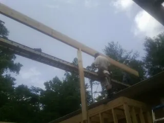 Carpenter setting a ridge beam over a new addition frame — Ice Dam Removal by Roofing Brothers in Novi