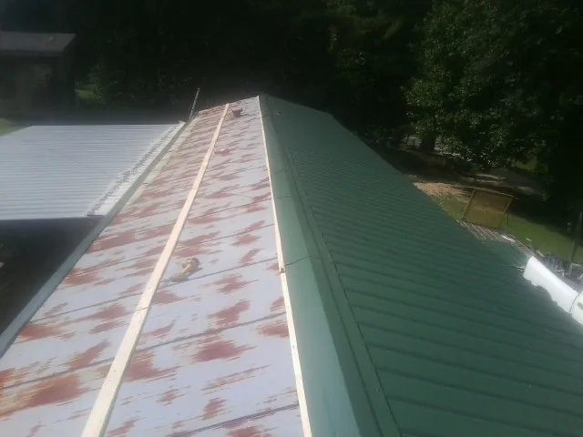 Old rusted panels beside newly installed green metal roofing — Wind Damage Roof Repair by Roofing Brothers in Novi