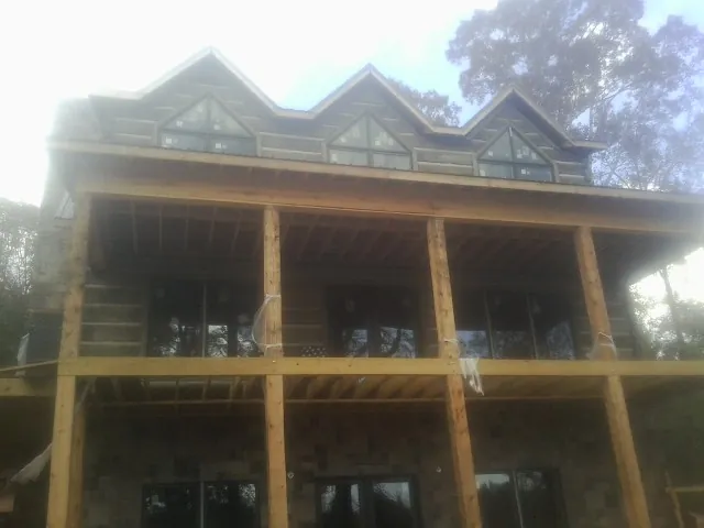 Dormers and porch framing on a large log home under construction — Roof Coating work by our crew in Novi