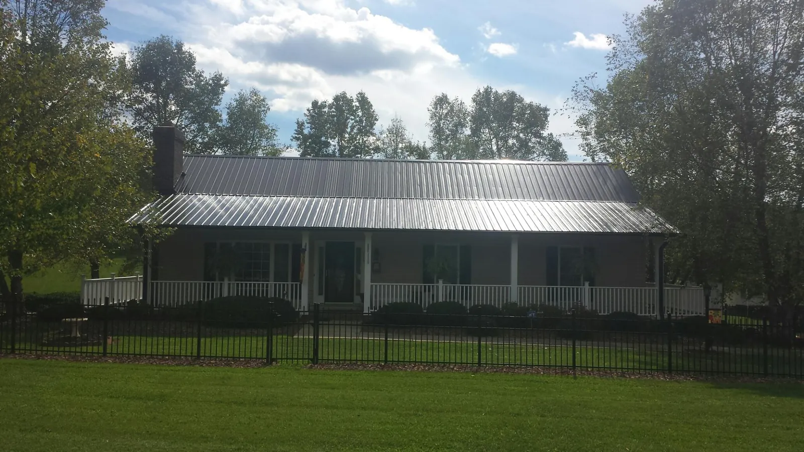 Gray metal roof on a brick ranch with a full width front porch — Gutter Guard Installation work by our crew in Novi