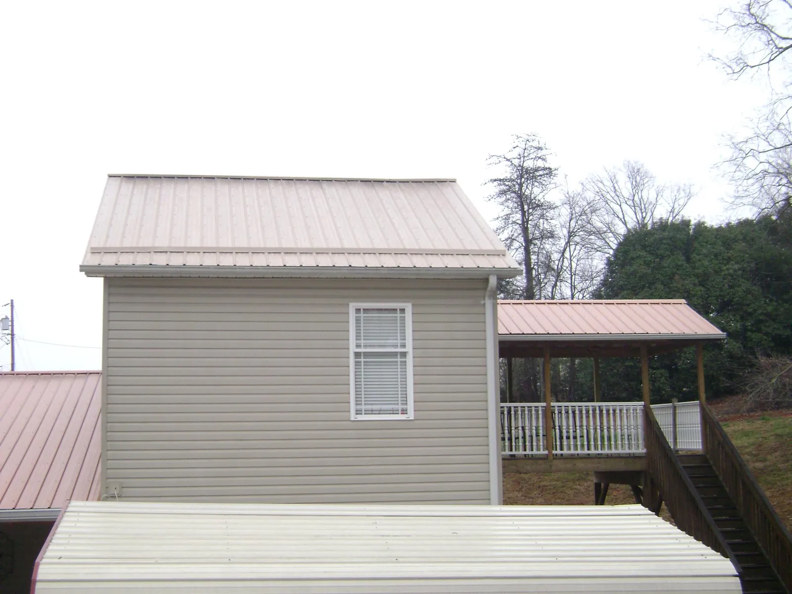Tan metal roofs on a two story addition and attached porch, from a Roof Replacement job in Novi