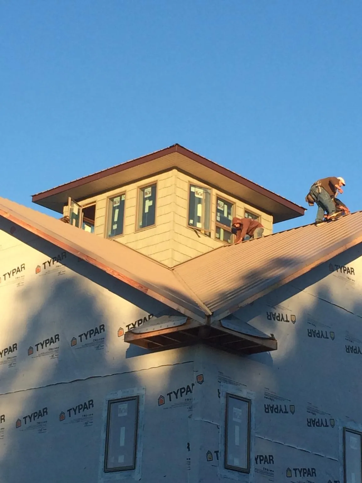 Roofers working around a rooftop cupola on a new metal roof at sunset — Roof Waterproofing in Novi by Roofing Brothers